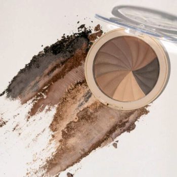 Polvo compacto de maquillaje en tonos marrones y beige abierto junto a pigmento esparcido en trazos, mostrando varias tonalidades para contorno y un acabado impecable pensado para profesionales.