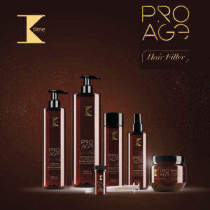 Conjunto de productos capilares en envases marrón ámbar con detalles dorados y el logo "K" y la marca "PRO AGE", dispuestos sobre fondo marrón e incluyendo dos botellas con dispensador, un frasco alto, un spray, un bote con tapa, un vial y una jeringa, transmitiendo diseño elegante y alta calidad.