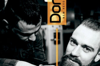 Barbero concentrado recortando con tijeras la barba de un cliente que mira a cámara en un salón, mostrando cuidado profesional y un ambiente moderno ideal para arreglos de barba.