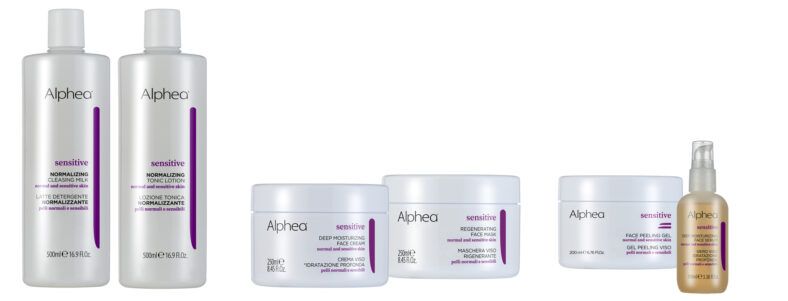 Conjunto de productos faciales Alphea Sensitive alineados sobre fondo blanco: dos botellas altas, tres tarros de cremas y un frasco con dosificador en envases blancos con detalles morados que transmiten alta calidad.