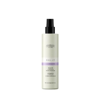 Botella dispensadora tipo spray de loción iluminadora para cabello en envase crema con banda lila y tapa negra, diseñada para uso profesional.