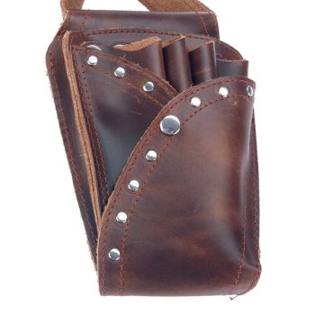 Estuche de cuero marrón con remaches y varios compartimentos que sostiene tijeras y herramientas de corte, diseñado para uso en peluquería.