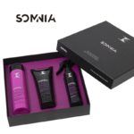 Set de peluquería en caja negra con interior morado que muestra tres productos para el cuidado del cabello —una botella, un tubo y un spray— dispuestos ordenadamente.