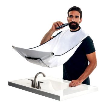 Hombre recortando la barba con una recortadora mientras una capa colectora sujeta al cuello desvía el pelo hacia el lavabo, representando una escena de peluquería.