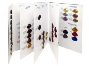 Carta desplegable con muestras físicas de color de cabello organizadas en paneles blancos que muestran mechones en una gama de rubios, castaños, cobrizos, rojos y tonos intensificadores para ayudar a estilistas y salones de belleza a comparar matices.