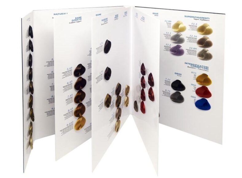 Carta desplegable con muestras físicas de color de cabello organizadas en paneles blancos que muestran mechones en una gama de rubios, castaños, cobrizos, rojos y tonos intensificadores para ayudar a estilistas y salones de belleza a comparar matices.