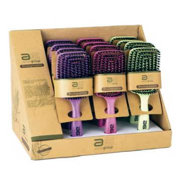 Expositor con varios cepillos planos tipo paddle de colores morado, rosa y verde en empaques de cartón biodegradables, presentados para uso en peluquería.