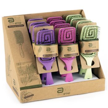 Expositor con varios cepillos tipo paleta acolchados biodegradables en tonos morado, rosa y verde presentados en una caja de cartón para venta en peluquería.