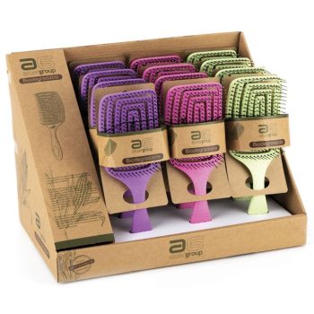 Expositor de cartón con filas de cepillos tipo paleta biodegradables en colores verde, rosa y morado, con cerdas en almohadilla, asas texturizadas y etiquetas kraft que indican Biodegradable, imagen que transmite alta calidad.