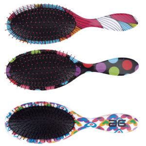 Tres cepillos de pelo ovalados con cojín negro y púas rematadas en rosa, mangos ergonómicos con estampados vibrantes (rayas, lunares y corazones) profesional.