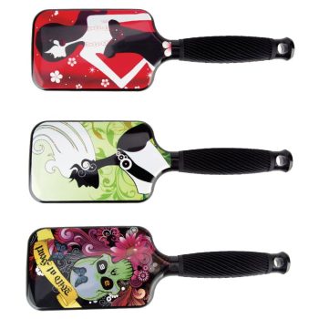 Tres cepillos planos tipo paddle con mango negro y respaldos decorados con motivos distintos —silueta femenina sobre fondo rojo, silueta ondulada sobre fondo verde y diseño floral con calavera sobre fondo oscuro— destinados a peluquería.