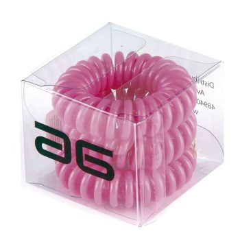 Una caja transparente contiene varios coleteros elásticos en espiral de color rosa apilados, accesorios de peluquería.