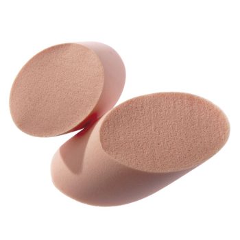 Dos esponjas de maquillaje ovaladas de espuma color piel sobre fondo blanco, asociadas a peluquería y con superficie porosa que sugiere una entrega uniforme del producto.