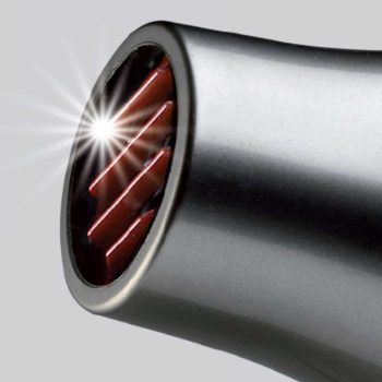 Primer plano del cono metálico de un secador de pelo moderno con rejilla interior roja y un destello brillante, equipo típico de peluquería.