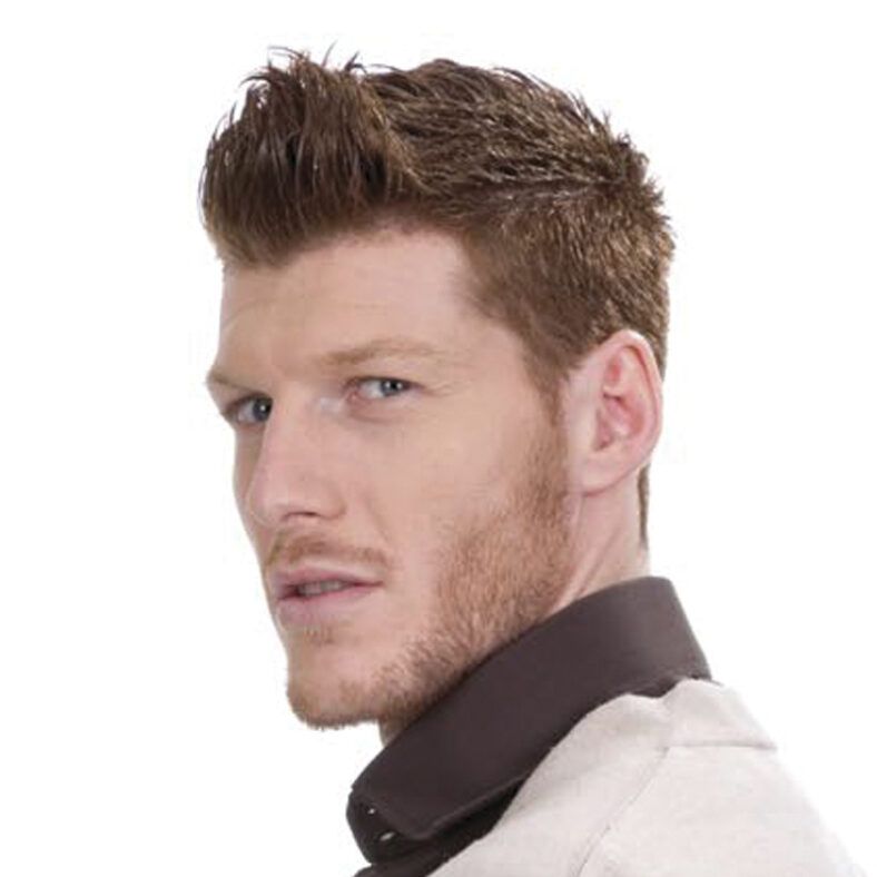 Hombre joven de perfil con barba corta y cabello castaño peinado hacia arriba, mirando por encima del hombro con expresión seria y aspecto profesional.