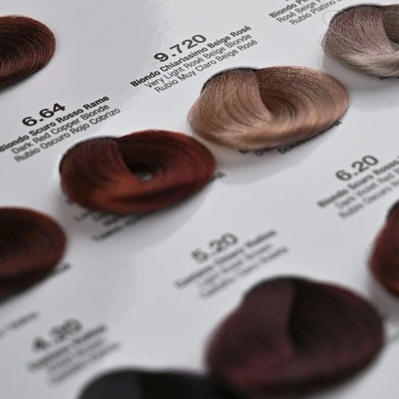 Muestra de carta de color con mechones organizados que exhiben tonos rubios, castaños y rojizos sobre fondo blanco, con etiquetas impresas y brillo sedoso que transmite alta calidad y sugiere una oferta para salones de belleza.