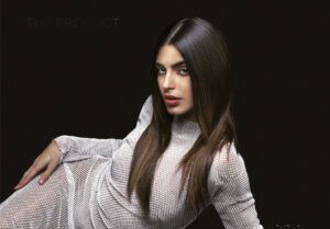 Mujer recostada sobre fondo negro con cabello largo y lacio peinado con raya en medio, maquillaje definido y vestido blanco de malla, imagen para salón de belleza.