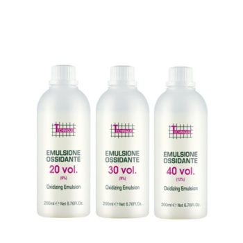 Tres envases blancos de emulsión oxidante para uso profesional en 'peluquería' alineados sobre fondo blanco.