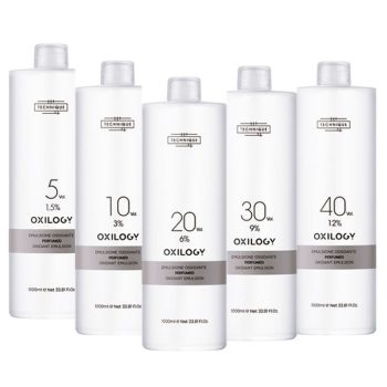 Cinco frascos blancos de emulsión oxidante para salón con diseño minimalista y etiqueta de la marca Oxilogy alineados en fila que transmiten aspecto profesional y garantía implícita de calidad.