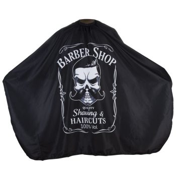Capa de barbería negra con gran estampado blanco de calavera con peinado y bigote y texto "Barber Shop", diseñada como producto profesional para cortes y afeitados.