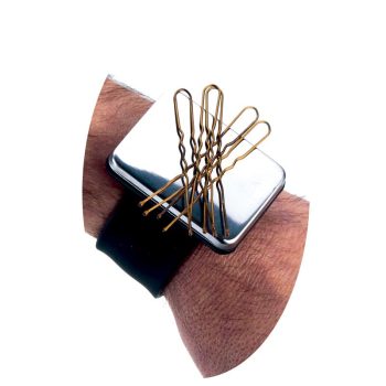 Pulsera magnética de alta calidad con una placa metálica rectangular y correa negra que sostiene varias horquillas doradas en la muñeca de un brazo velludo, ofreciendo una sujeción potente.