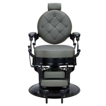 Silla de barbero profesional en cuero gris con respaldo redondo capitoné, reposabrazos metálicos, reposapiés y base giratoria, de líneas robustas y un sutil toque barato.