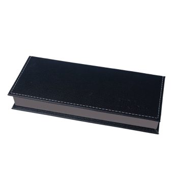 Estuche rectangular cerrado forrado en cuero negro con costuras blancas visibles sobre fondo blanco, de aspecto sobrio y profesional que sugiere uso en peluquería.