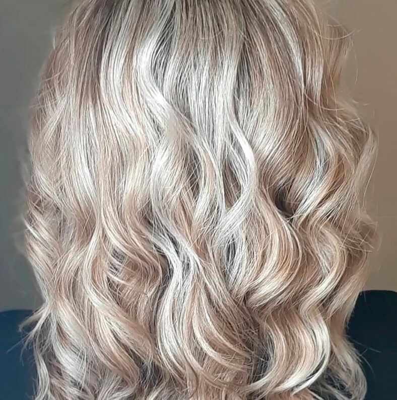 Cabello rubio claro ondulado visto desde atrás con mechones brillantes y textura suave, peinado profesional de alta calidad que realza mejor las ondas.