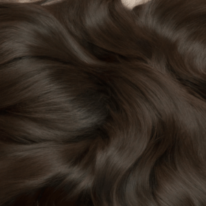 Brillo sedoso y ondas suaves de cabello castaño oscuro en primer plano, ideal para mostrar estilos de 'peluquería'.