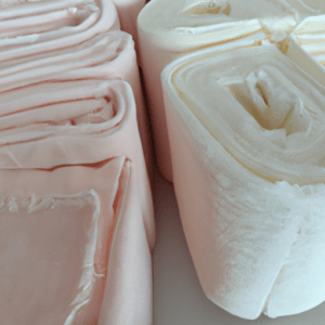 Primer plano de rollos acolchados en tonos rosa y crema con textura suave y pliegues marcados, acabado pensado para uso profesional y certificado.